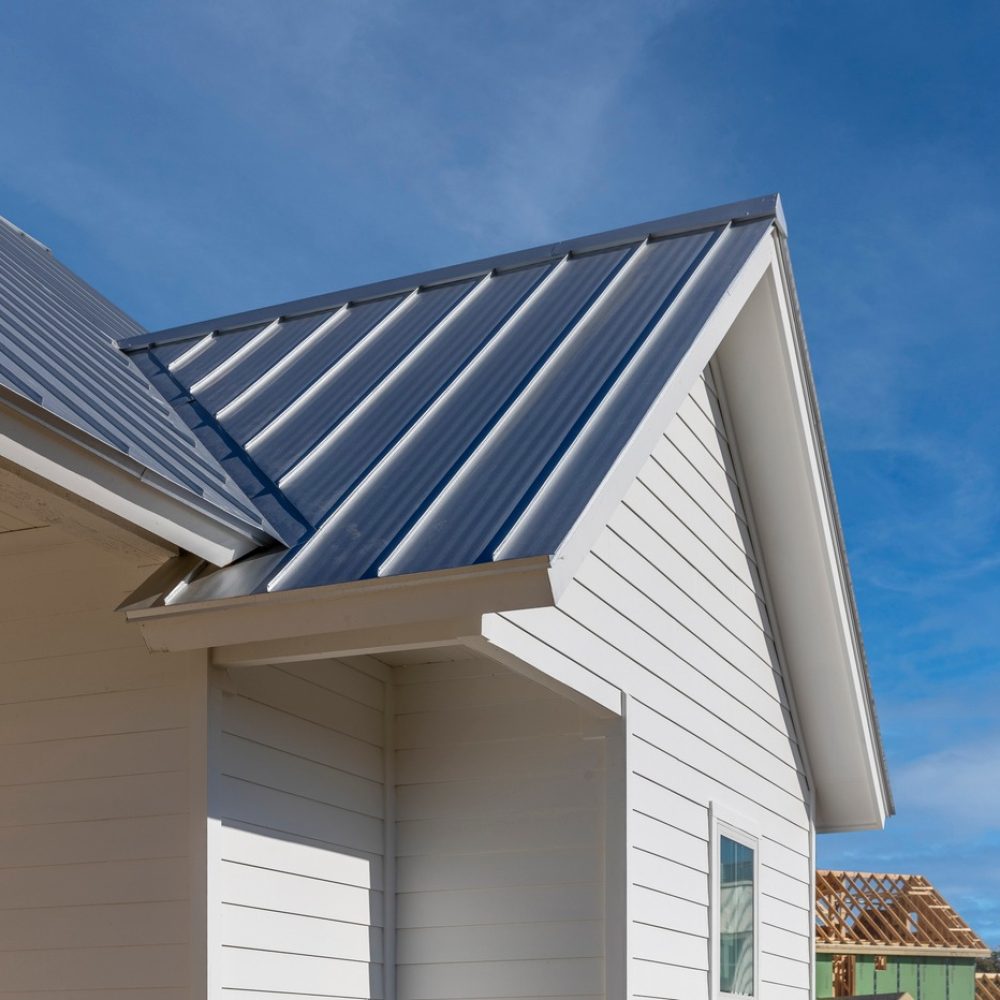 A black new roof and white siding of a house that is new and under construction.