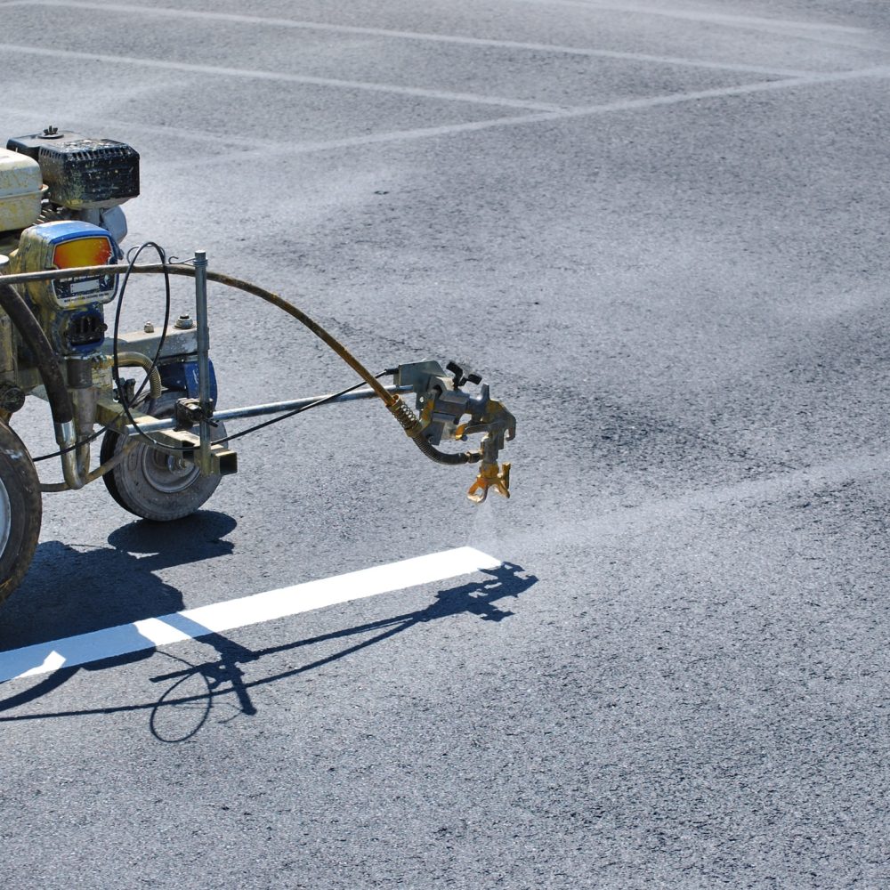 Striping machine painting lines onto fresh asphalt.
