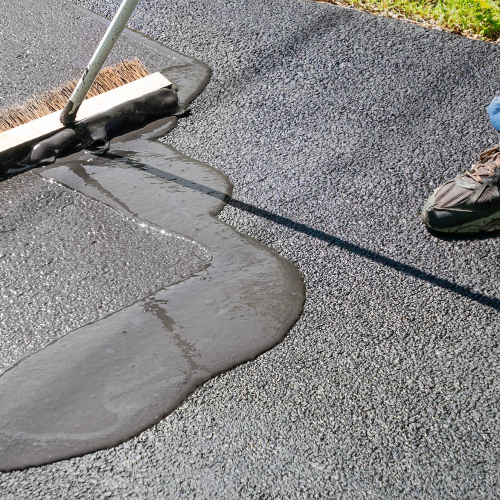 Spreading asphalt resealer onto driveway for maintenance